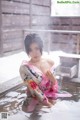 A woman in a pink kimono sitting in a pool of water.