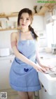 A woman in a blue and white apron standing in a kitchen.