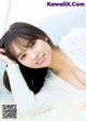 A woman laying on top of a white fur covered bed.