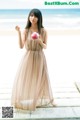 A woman standing on a wooden dock holding a cupcake.