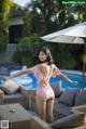 A woman in a pink bathing suit standing by a pool.