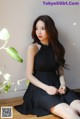A woman in a black dress sitting on the floor.