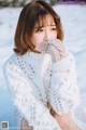 A woman in a white sweater sitting in the snow.