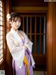 A woman in a purple and white kimono posing for a picture.