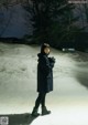 A woman standing in the snow at night. 