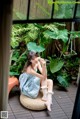 A woman sitting on a stool in front of a window.