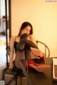 A woman sitting at a table with a pair of red shoes on it.