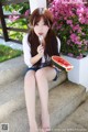 A woman sitting on the steps eating a slice of watermelon.