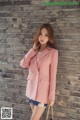 a woman wearing a pink blazer and shorts standing in front of a brick wall