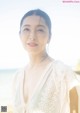 A woman in a white dress standing on a beach.