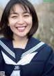 A woman in a sailor outfit smiles at the camera.