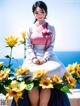 A woman sitting on a bench surrounded by yellow flowers.