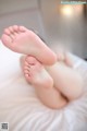 A woman laying on top of a bed with her feet up.