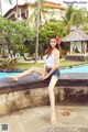 A woman sitting on the edge of a swimming pool.