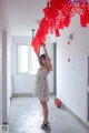 A woman in a white dress holding up a red chandelier.