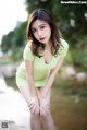 A woman in a green dress posing by a river.