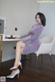 A woman in a purple dress sitting on a white chair.