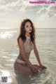 A woman in a white bikini sitting in the water.